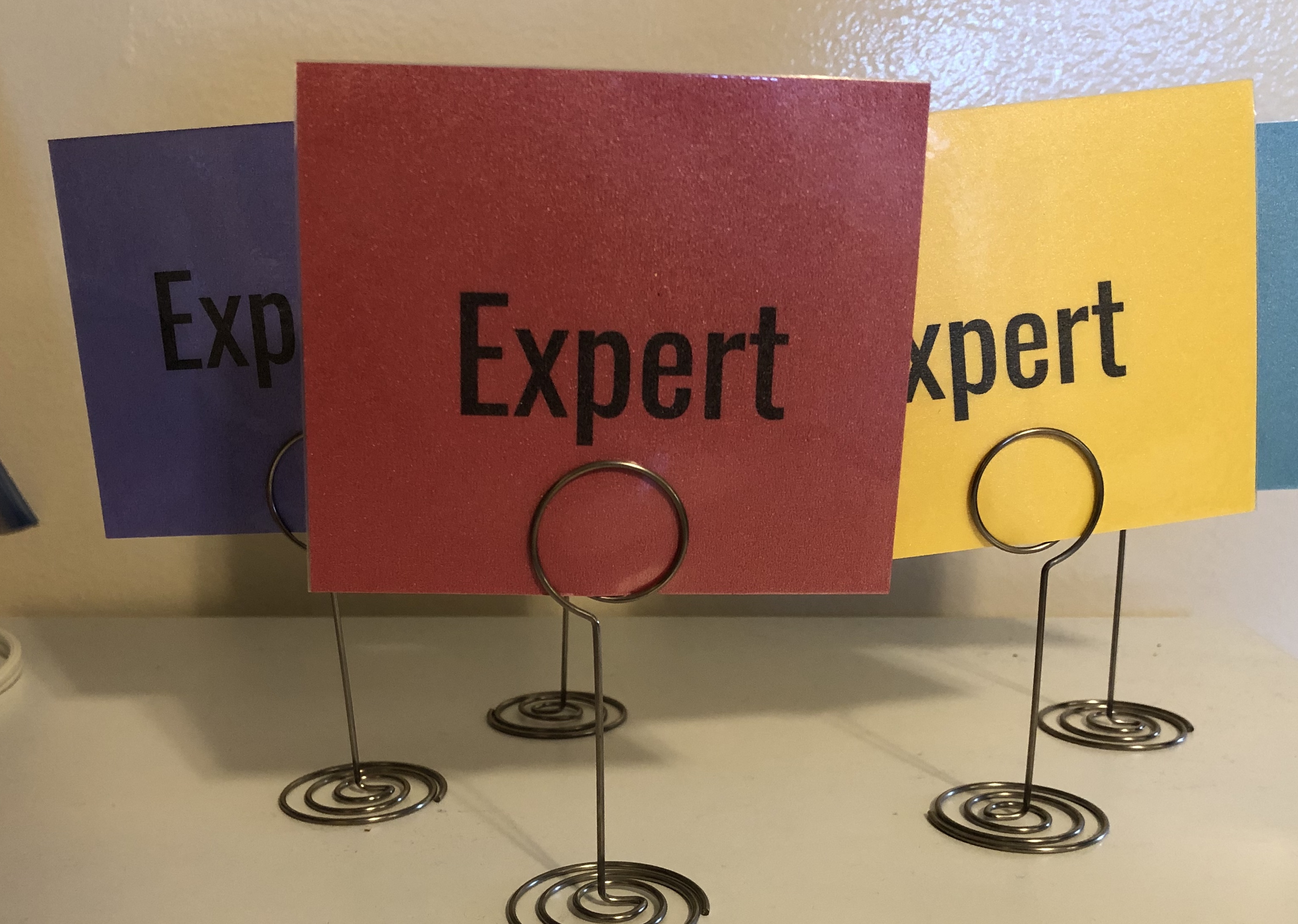 Card stock cards in multiple colors labeled "expert" and held up by table number holders